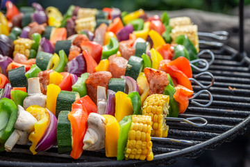Tasty skewers on grill with vegetables and meat in summer