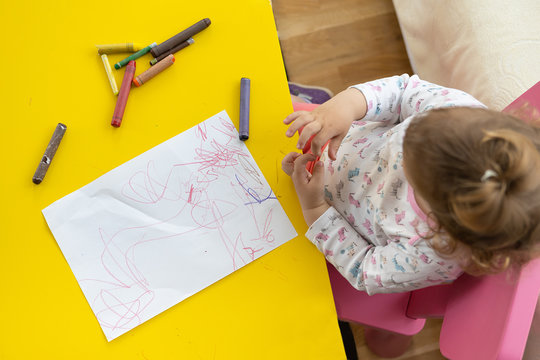 toddler girl drawing with crayons on paper