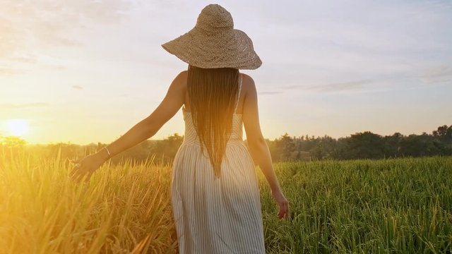 Sensual young woman in white dress enjoying in violet lavender filed at beautiful summer sunset. Young female enjoying nature and sunlight in straw field.
