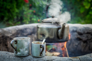 Fresh and hot coffee with kettle on campfire