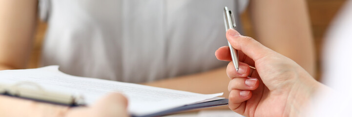 Male hand holding silver pen offering some papers for approval terms of cooperation pact