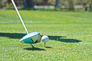 A golfer is about to strike at a ball sitting on a tee.