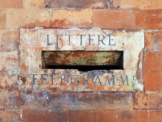 Old mailbox slot for letters and telegrams in a brick wall in Bologna city, Italy