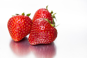 Three ripe strawberries on a white background with water drops. Macro. Close-up.