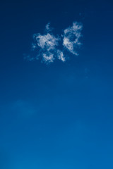 Fototapeta na wymiar Wispy Cloud Alone on Vibrant, Deep Blue Sky