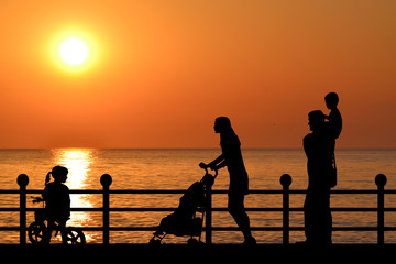 Fototapeta na wymiar Family on the waterfront promenade at sunset
