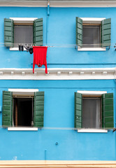 Fototapeta na wymiar Colourful house on the island of Burano. The facade of a blue house with a laundry rack outside in Burano, Venice, Italy. Burano is near Venice, and is famous for its canals and charming. - Immagine