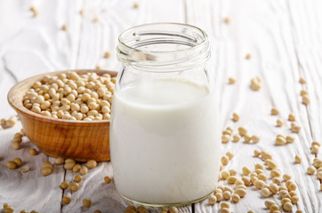 Non-dairy alternative Soy milk or yogurt in mason jar on white wooden table with soybeans in bowl aside