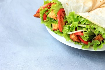 Doner kebab on a white plate. Shawarma with meat, onions, salad and tomato on on gray background. Eastern food.
