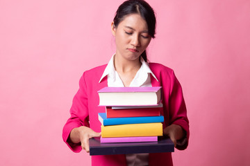 Unhappy young Asian woman studying  with may books.