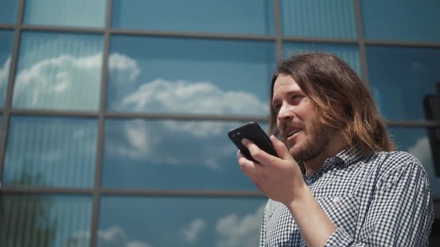 Man using the voice recognition on the phone, audio message ai speech helper, student male outdoor