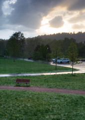 Lone bench in open field under rain and cloudy sky