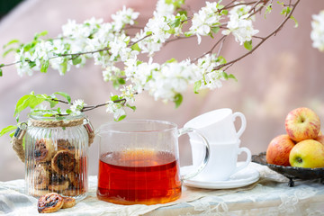 Tea party outdoor on blossom apple tree background with cookies and apples 