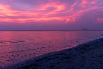 A beautiful sunset on a beach in Koh Lanta, Thailand, the sky ablaze with purples and blues reflected in the ocean, nobody in the image