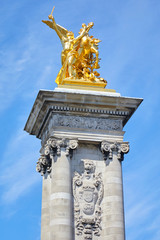 Fototapeta na wymiar Alexandre III bridge golden statue with winged horse and column in a sunny summer day, blue sky in Paris, France.