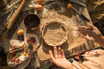 woman in gentle sundress cooking a sweet pie with fresh apricots on a sunny summer day