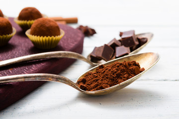 chocolate truffles, cocoa powder, broken dark chocolate on white wooden
