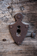 Old keyhole on a wooden door. Vintage metal element.