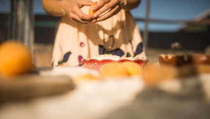 woman in gentle sundress cooking a sweet pie with fresh apricots on a sunny summer day
