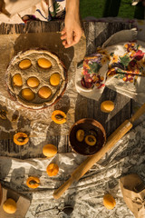 woman in gentle sundress cooking a sweet pie with fresh apricots on a sunny summer day