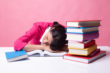 Exhausted Young Asian woman sleep with books on table.