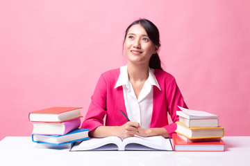 Young Asian woman read a book with books on table.