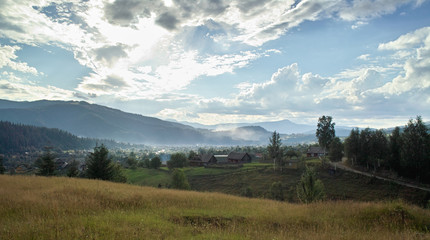 Mystery fog over the village on Carpathian Mountains: View on village Mykulichin in the evening.