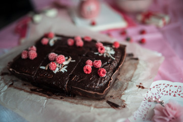 tasty homemade chocolate birthday cake decorated of some raspberries and candles served on the gentle pink background