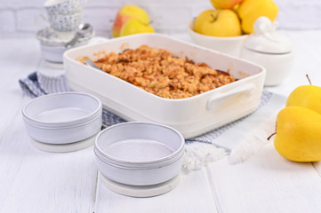 Apple pie in white ceramic baking dish. Homemade breakfast with apples and a la carte plates. Bright photo. Free space for text.