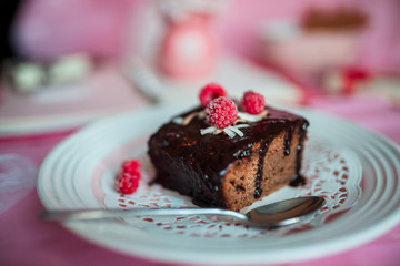 tasty homemade chocolate birthday cake decorated of some raspberries and candles served on the gentle pink background