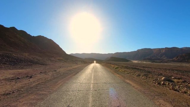 Driving footage on an empty old Desert road in wide view and lens flare.
