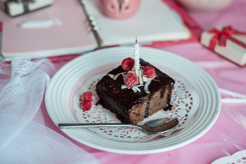tasty homemade chocolate birthday cake decorated of some raspberries and candles served on the gentle pink background