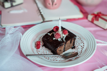 tasty homemade chocolate birthday cake decorated of some raspberries and candles served on the gentle pink background