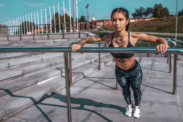 Athlete girl wrung out summer city. Sportswear leggings top sneakers, woman. Free space for text. The concept of fitness in fresh air, an active lifestyle workout. Tattoos on a tanned figure.