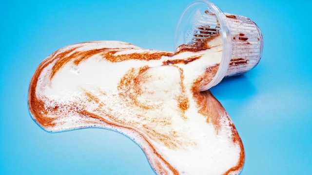 reverse of side view cup of chocolate flavor ice cream melting on blue time lapse