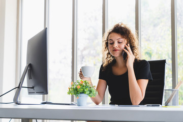 Young caucasian businesswoman smiling drinking coffee and using phone talking to partner in office