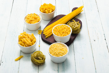 uncooked pasta variations on white wood table