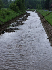 Water stream in river bed where water shouldn't be. Artificial created canal for transport some woods, small bags and so on. Floods in the Czech Republic, in may 2019