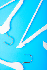 Some white clothes hangers isolated on a blue background. Flat lay. Concept view.