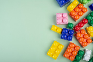 Colorful plastic construction blocks on green background. Copy space for text.