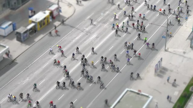 Many cyclists ride along the road. Bike ride on the street handheld tilt-shift shot from above.