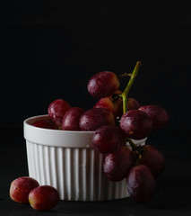 Red grape on the white bowl darkphoto