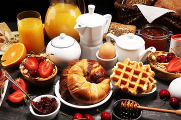 Huge healthy breakfast on table with coffee, orange juice, fruits, waffles and croissants. Good morning concept.