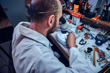 Smart watchmaker is restoring cutomer's watch at his own repairing studio.