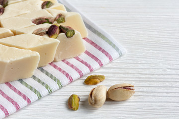 halva with pistachios on a white wooden background with a textile napkin