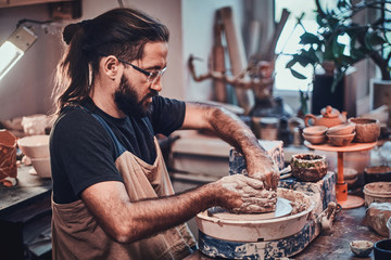 Man in glasses is working on his own clay project.