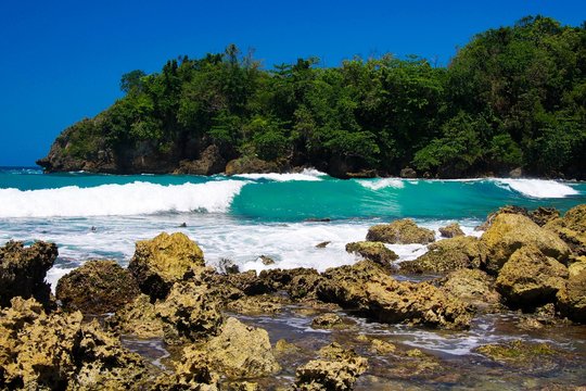 View beyond sharp rocks on turquoise rough sea with wave breakers and strong surf - Port Antonio, San San Beach, Jamaica © Ralf
