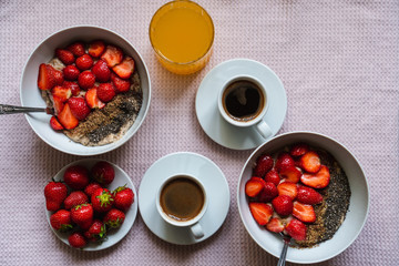 Vegan breakfast at home packed with nutrients, oatmeal porridge with fresh strawberries, chia and flax seeds, coffee and orange juice, top view. Healthy lifestyle concept.