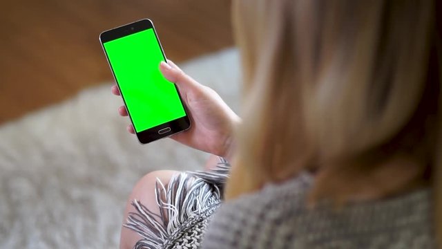 Female hand swiping up on a phone with a green screen