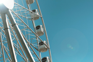 carousel attraction ride white ferris wheel in amusement park in front of blue sky bottom view